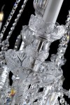 Une tulipe en verre taillé sous une ampoule de lustre
