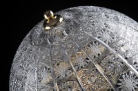 Détail de la gravure en dentelle sur l'abat-jour en verre d'une lampe décorative.