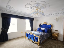 La version à 18 ampoules du lustre s'harmonise avec le lit double bleu de la chambre.