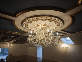 Des pièces basses du grenier d'une maison, à la décoration somptueuse, ornées de lustres en cristal aux couleurs chatoyantes