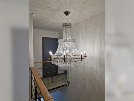 Ce lustre s'intègre parfaitement dans un intérieur minimaliste où le bois est présent sur la rampe.
