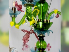 Des papillons en verre suspendus aux bras verts du lustre